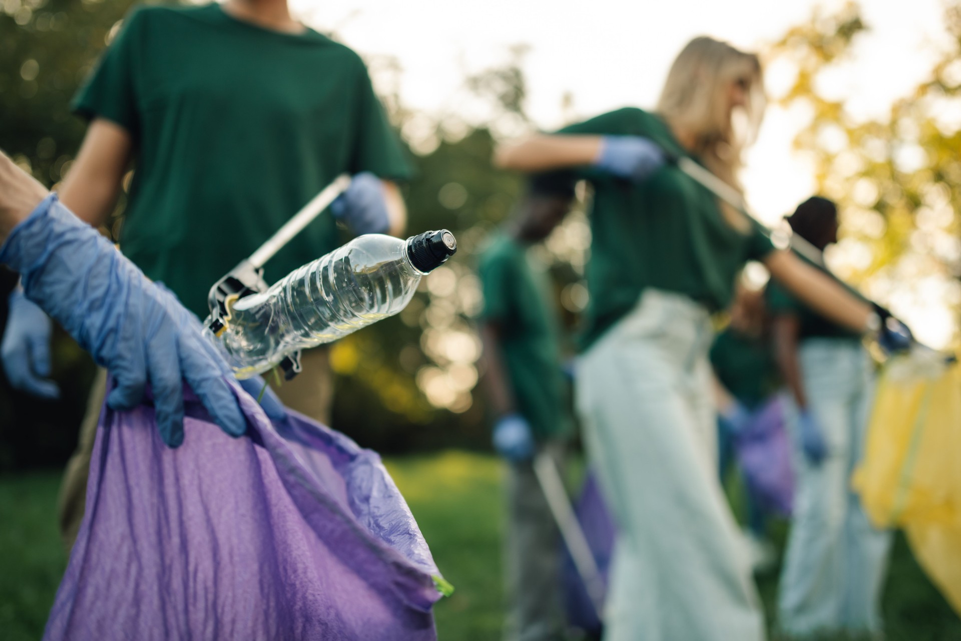 Volunteers collecting plastic bottle trash in park cleanup event